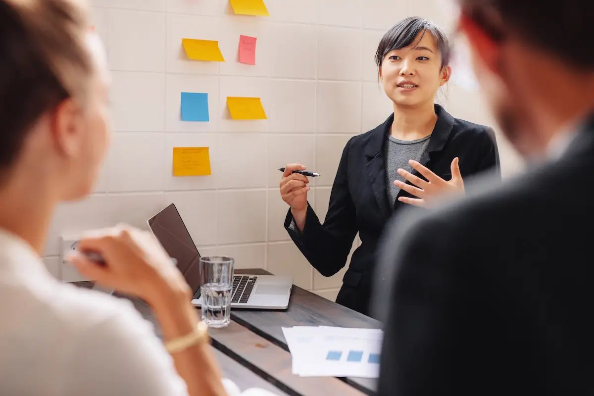 The file is an image of a woman giving a presentation to two people at a meeting.