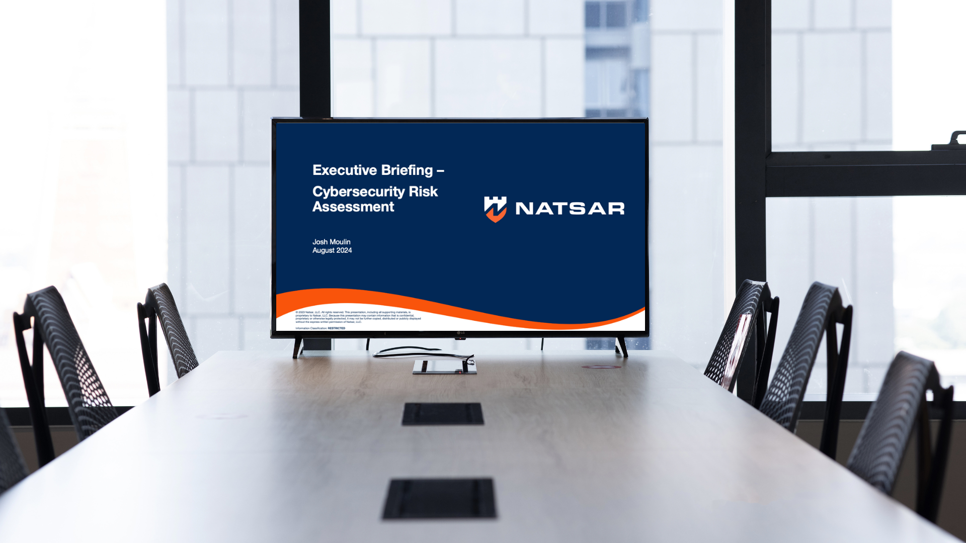 Boardroom with large TV showing briefing slide from Natsar