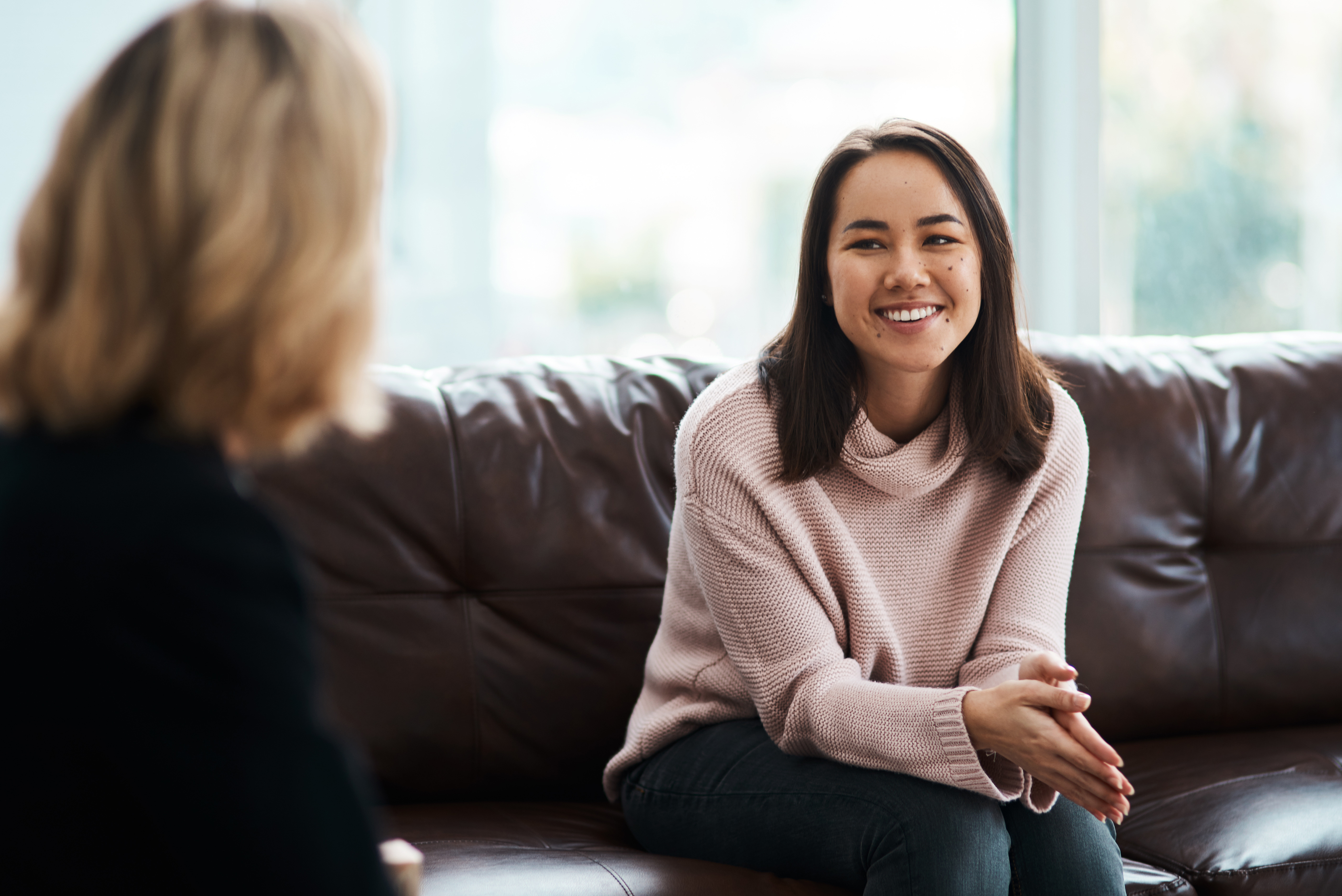 Woman sitting on a couch talking to another woman